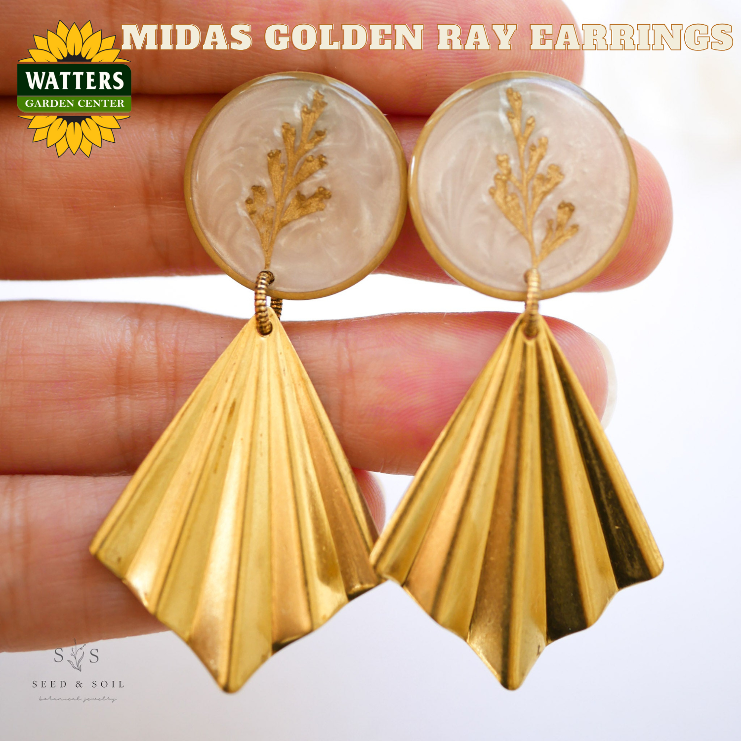 Gold earrings with leaf design held between fingers, Watters Garden Center logo visible.