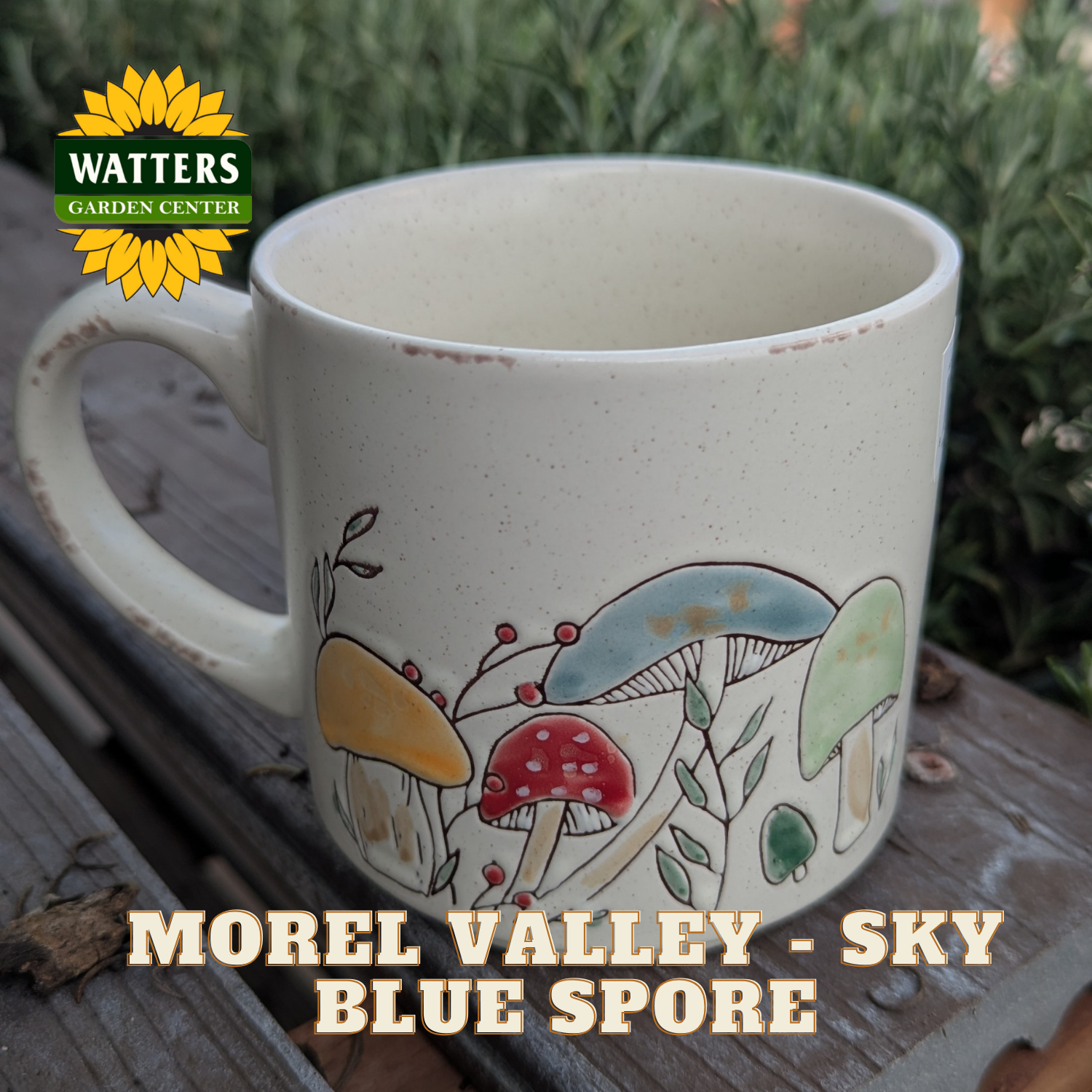 White mug with mushroom design on a wooden surface, featuring Watters Garden Center logo.