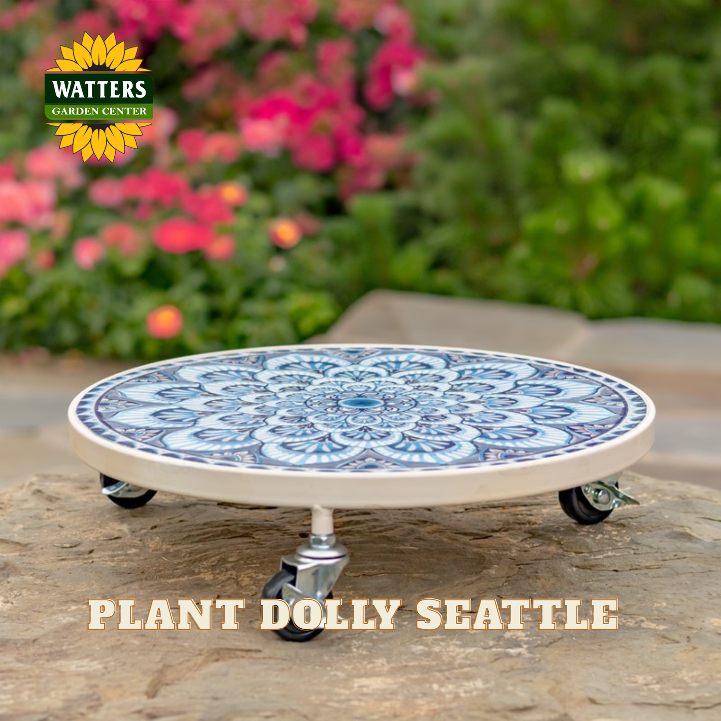 A round ceramic plant dolly with a blue and white mandala pattern on top, resting on a stone surface with a blurred garden background. The Watters Gardens Center logo is in the top-left corner, and the text 'PLANT DOLLY SEATTLE' is at the bottom.