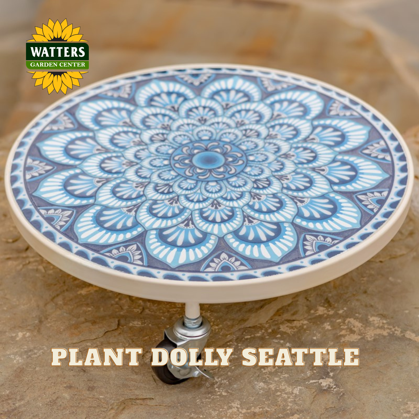 A round ceramic planter plate with a blue and white mandala pattern, mounted on a small wheeled stand, set against a stone background. The Watters Gardens Center logo is visible in the top left, and 'PLANT DOLLY SEATTLE' is written at the bottom.