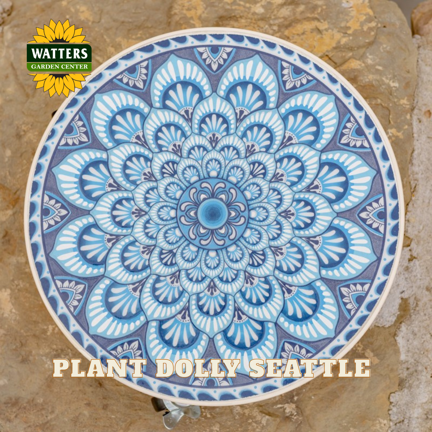 A round ceramic garden plaque featuring a detailed blue and white mandala design, displayed on a natural stone surface. The Watters Gardens Centre logo is visible in the top-left corner, and 'PLANT DOLLY SEATTLE' is written at the bottom.