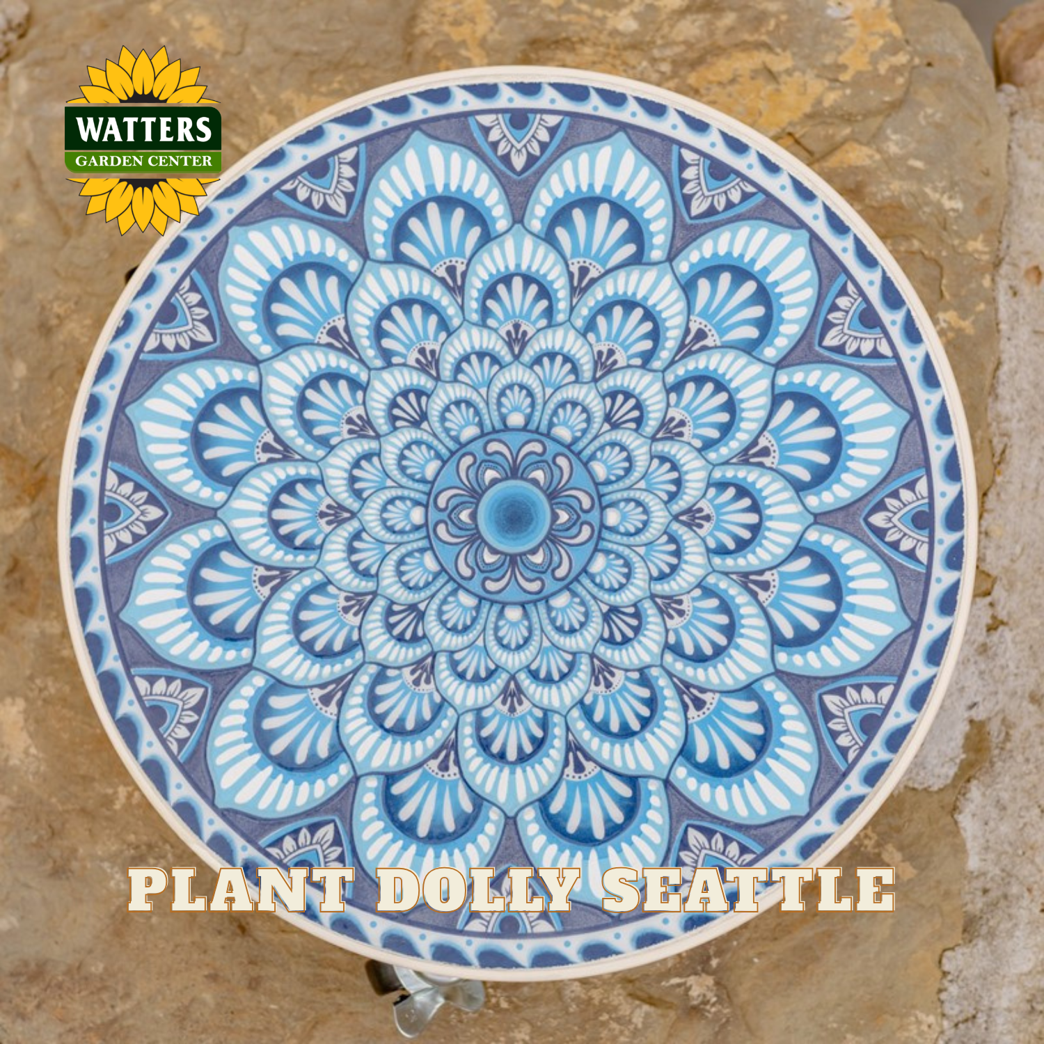 A round ceramic garden plaque featuring a detailed blue and white mandala design, displayed on a natural stone surface. The Watters Gardens Centre logo is visible in the top-left corner, and 'PLANT DOLLY SEATTLE' is written at the bottom.