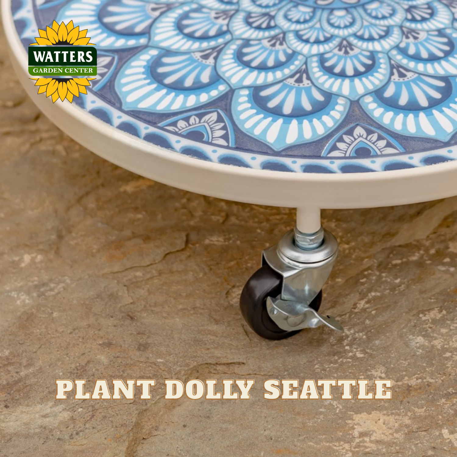 Close-up of a round plant dolly with a blue and white patterned tile top, supported by a white frame and a black caster wheel, sitting on a stone surface. The Watters Gardens Center logo appears in the top left, and the text 'PLANT DOLLY SEATTLE' is at the bottom.