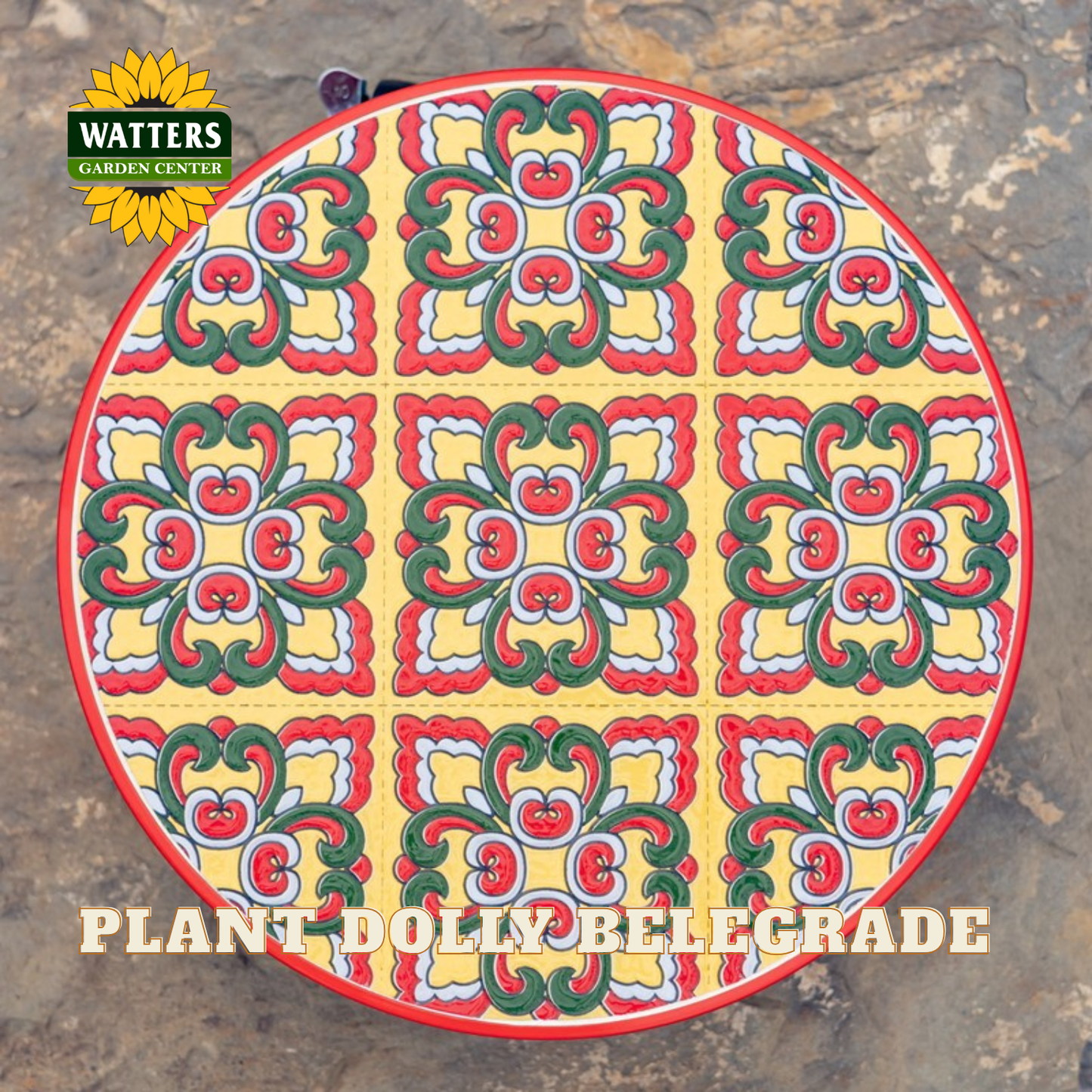 A round decorative sign or plaque featuring a colorful tile-inspired floral pattern with red, green, yellow, and white motifs, photographed outdoors on a stone surface. The Watters Gardens Center logo appears in the top-left corner, and the text 'PLANT DOLLY BELEGRADE' is printed along the bottom.