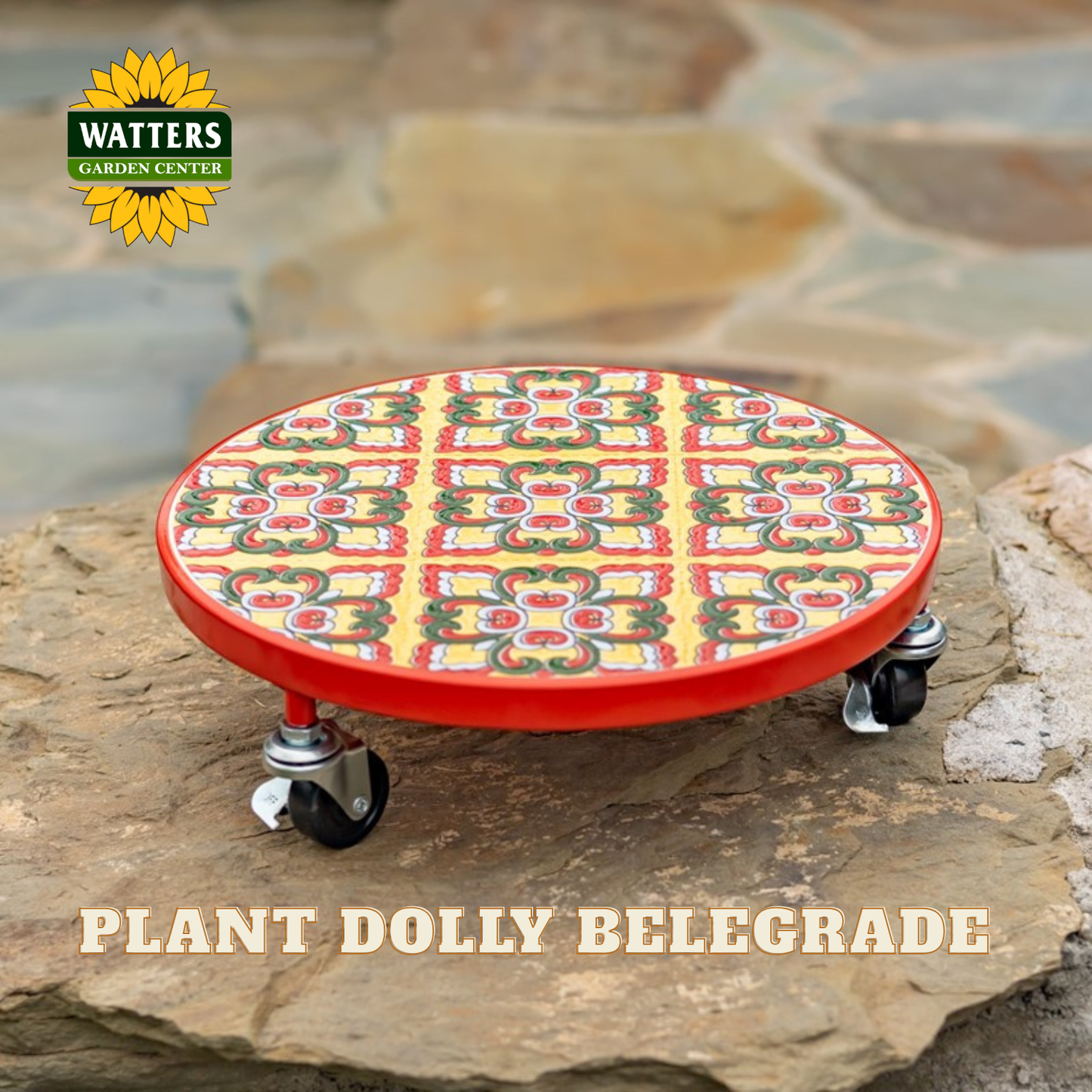 A red circular plant dolly with a colorful tiled pattern top and black caster wheels, shown outdoors on a stone surface. The Watters Gardens Center logo appears in the top-left corner, and the text 'PLANT DOLLY BELEGRADE' appears at the bottom.