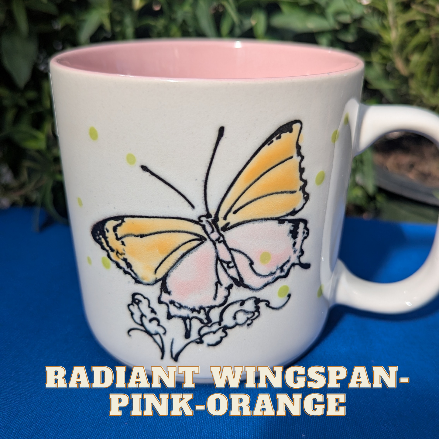 Mug with a butterfly design on a blue surface with greenery in the background