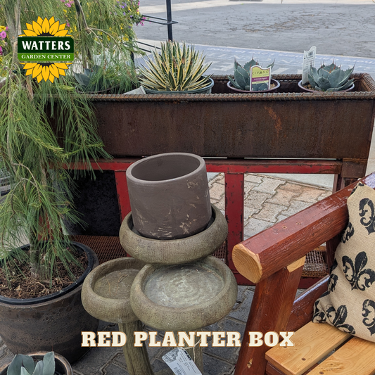 Red and bronze planter box in a garden setting.