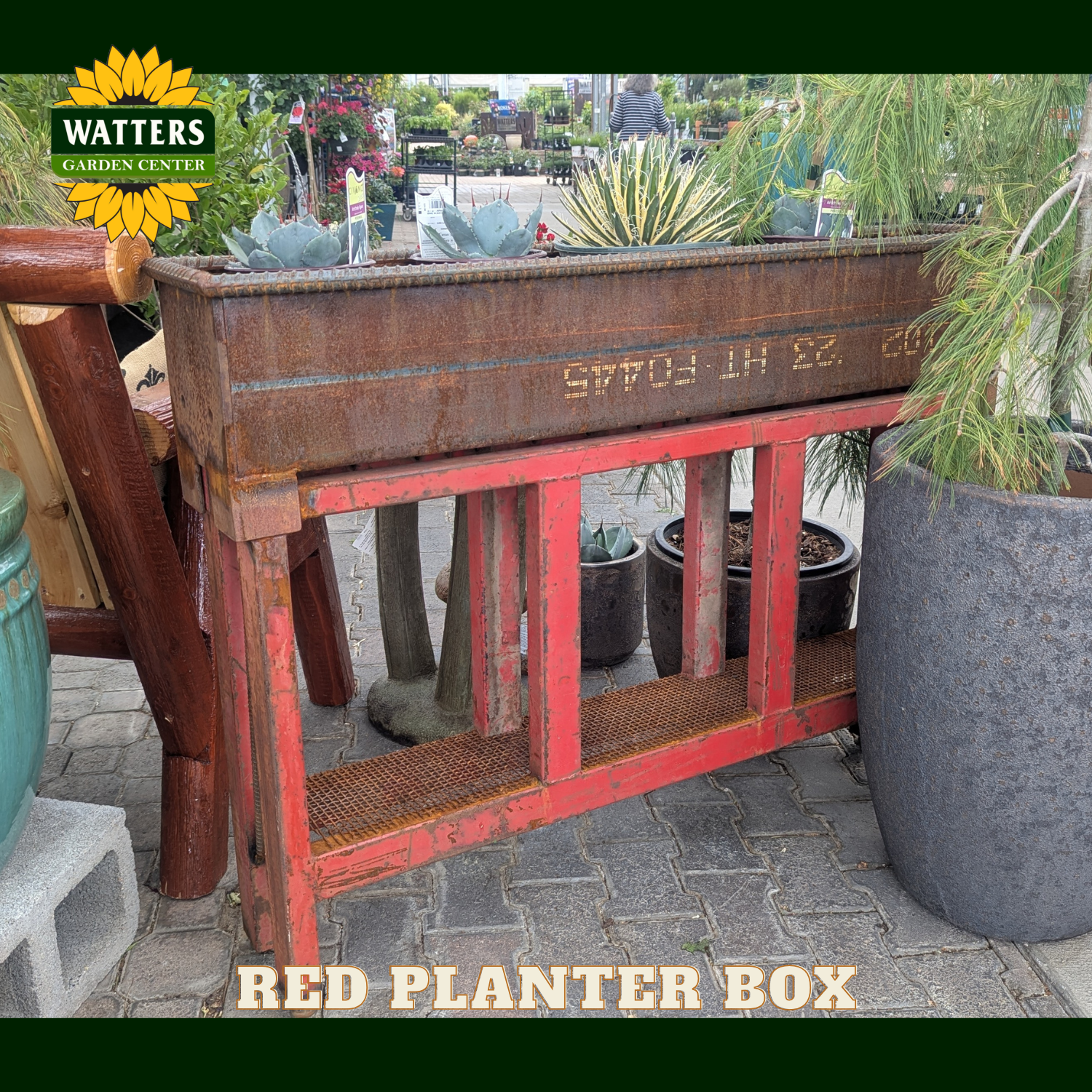 Red and bronze planter box in a garden setting.