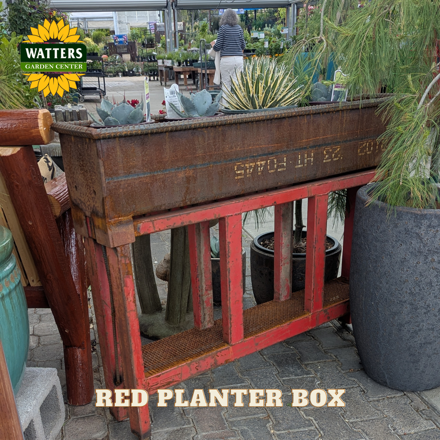 Red and bronze planter box in a garden setting.