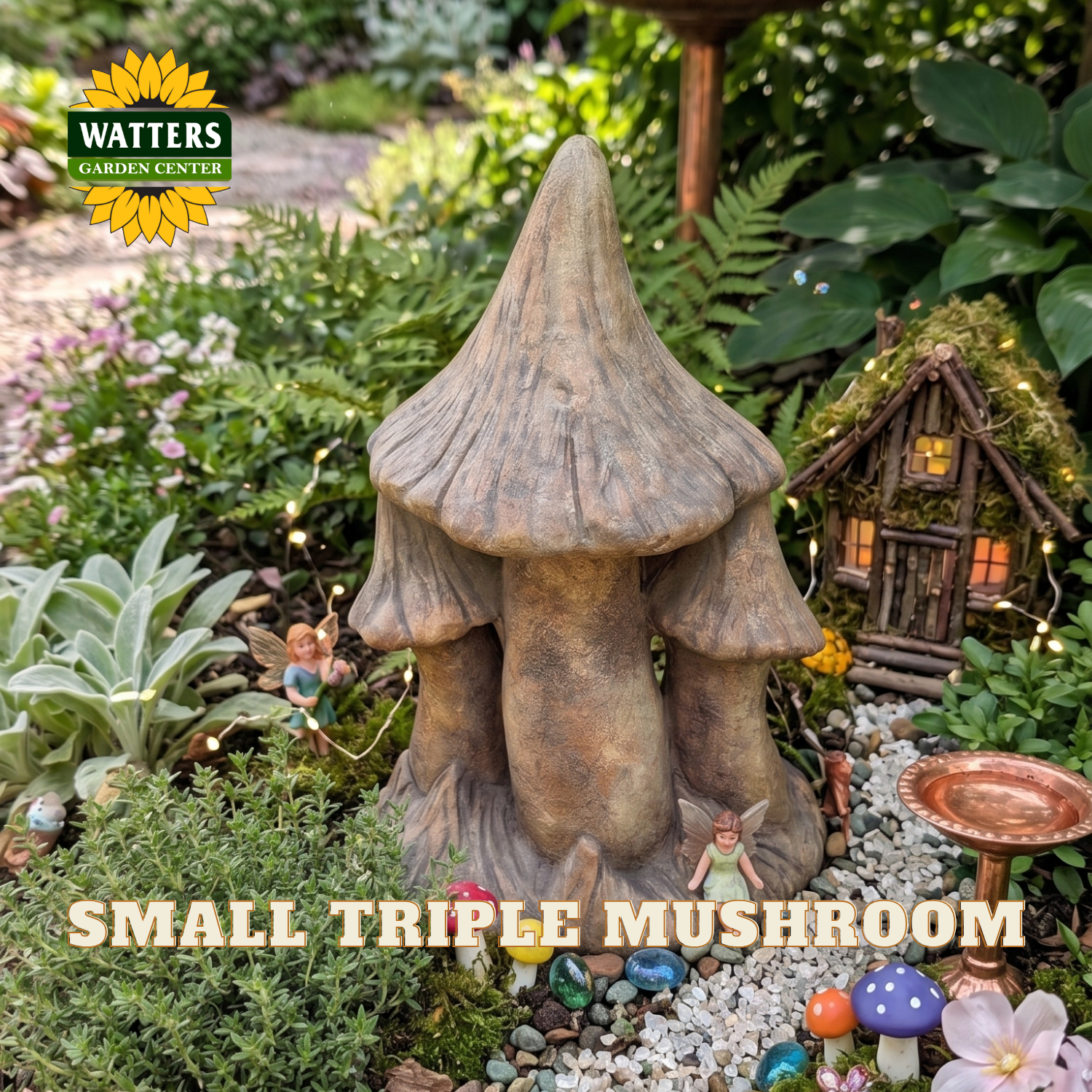 A small triple mushroom garden stake ornament displayed in a lush garden setting with fairy lights, a miniature cottage, and other garden decorations. The Watters Gardens Center logo is visible in the top left, and 'SMALL TRIPLE MUSHROOM' is written in text at the bottom.