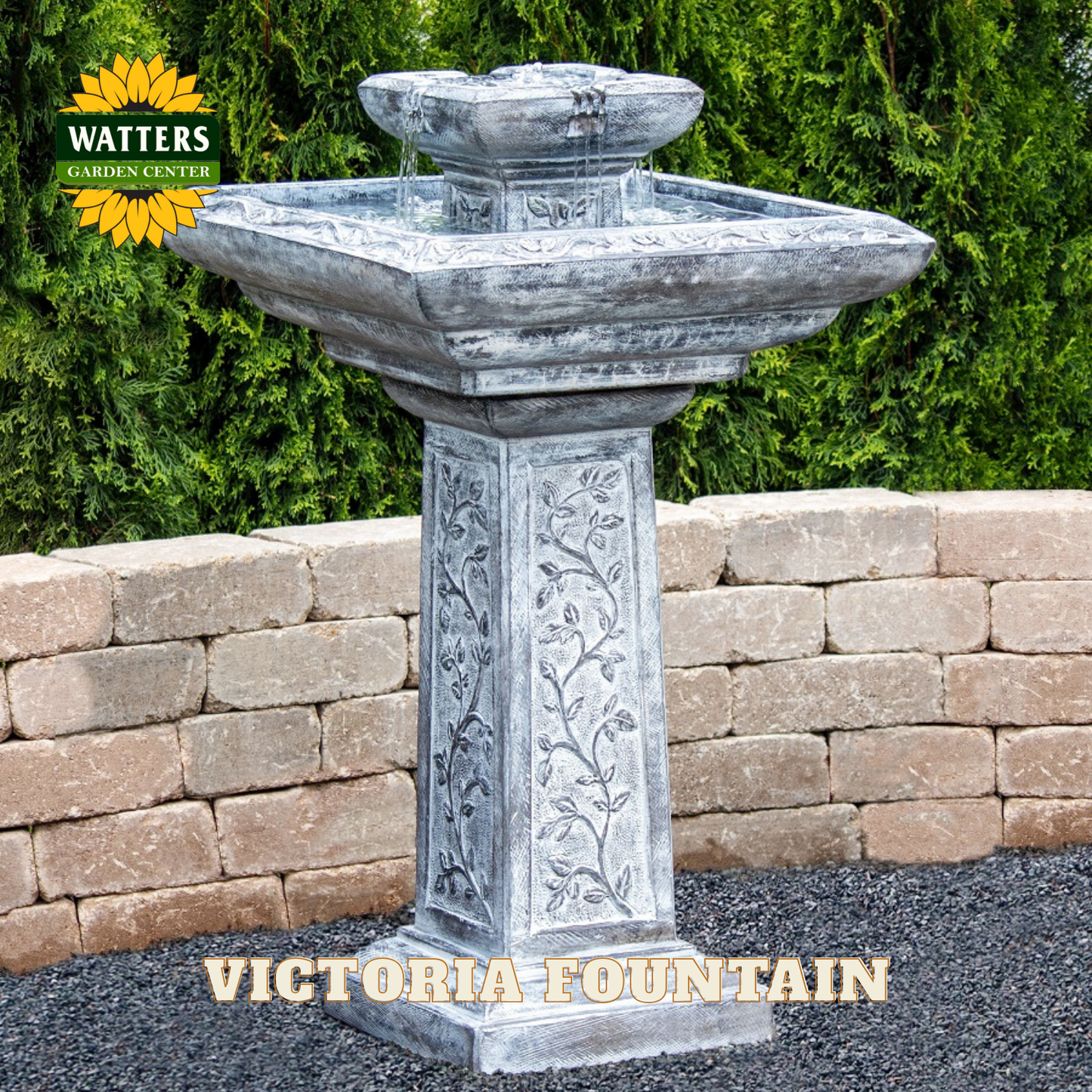 Decorative stone fountain with 'Watters Garden Center' branding against a brick wall and greenery background.