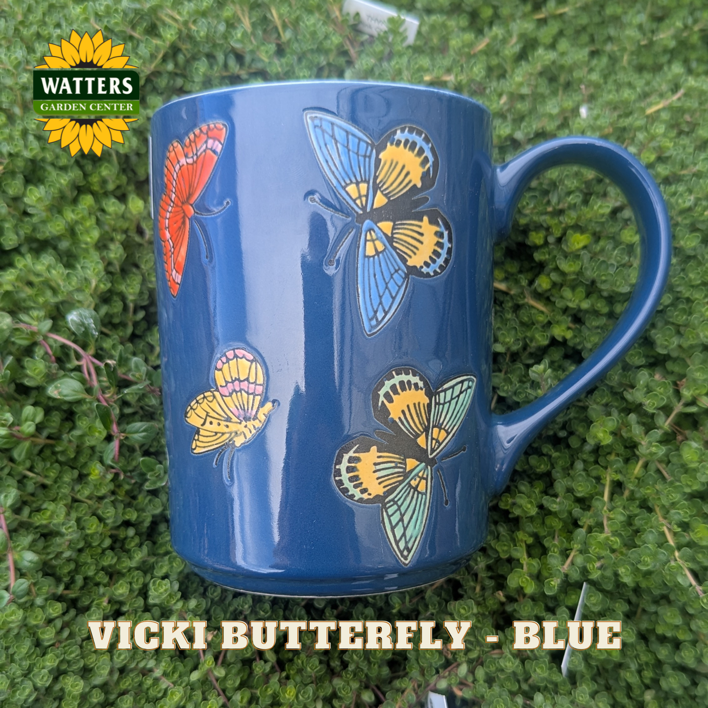 Blue mug with butterfly designs on a green leaf background, featuring Watters Garden Center logo.