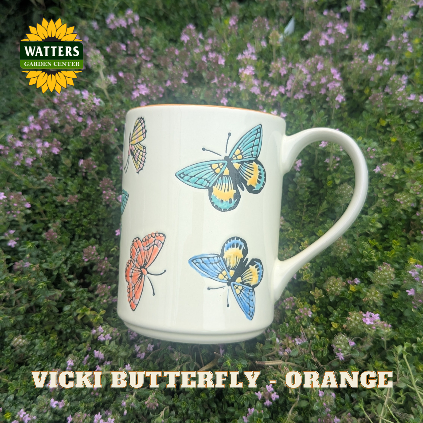 Mug with butterfly design on a natural background, featuring Watters Garden Center branding.
