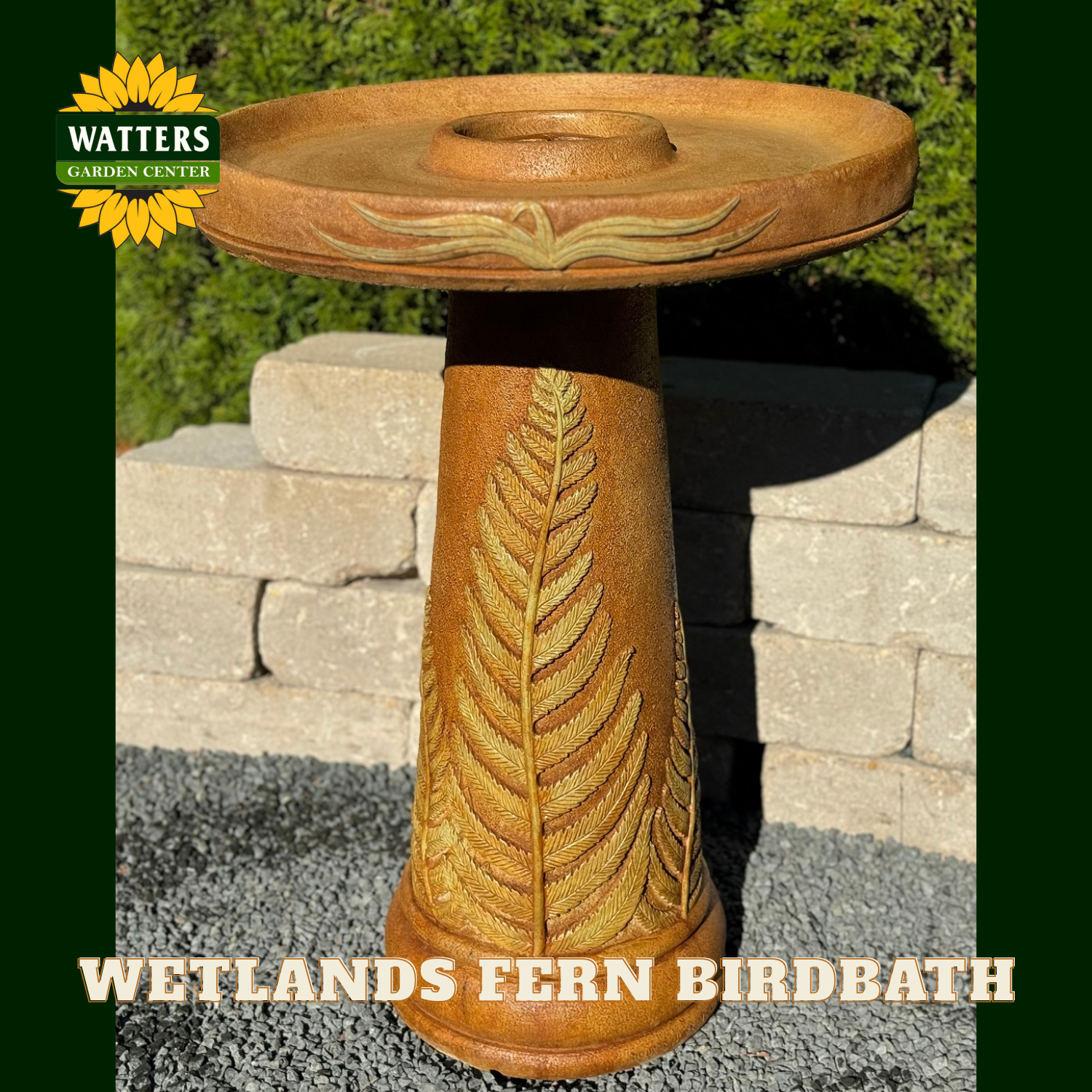 Wooden bird bath with fern design on a stone patio, branded 'Watters Garden Center'.