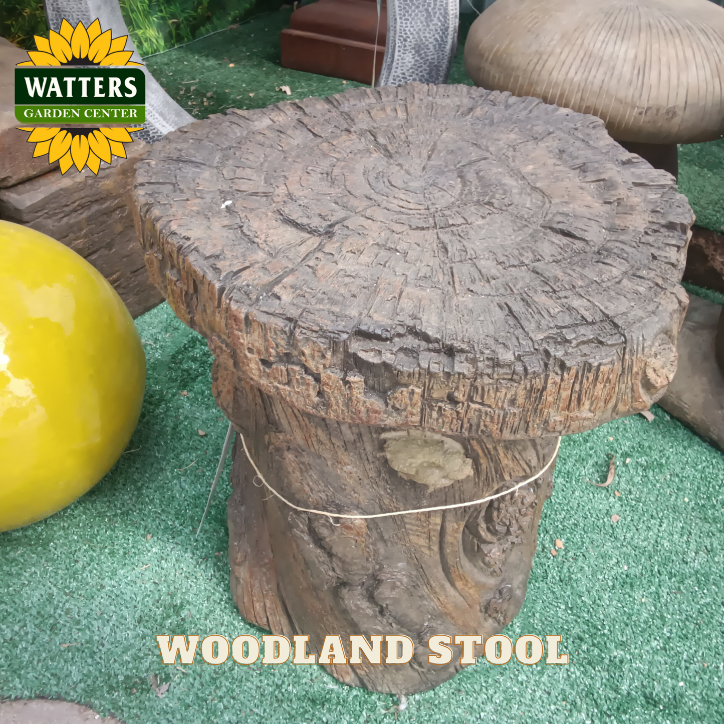 Wooden stool made from a tree stump with 'Watters Garden Center' branding.