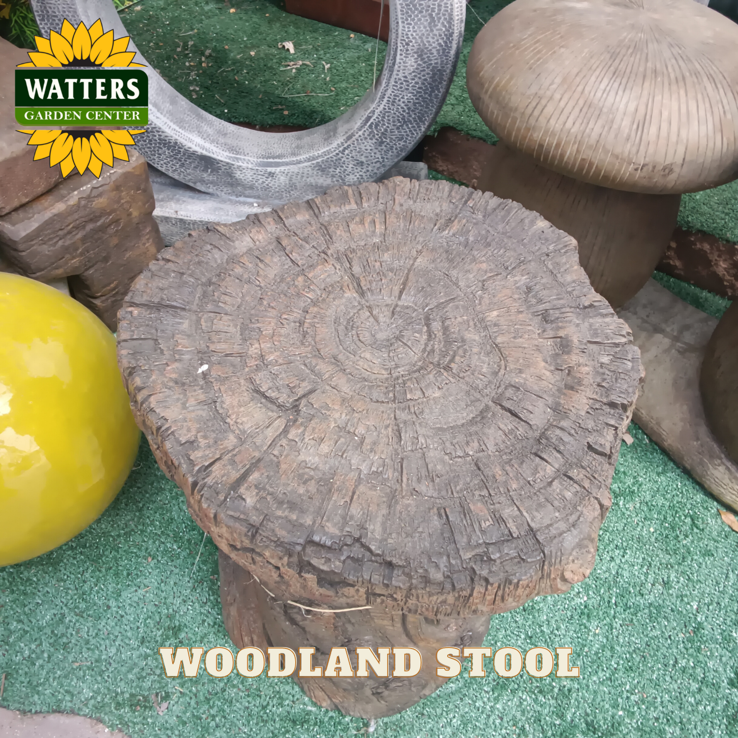 Wooden stool with 'Watters Garden Center' branding on a green surface.