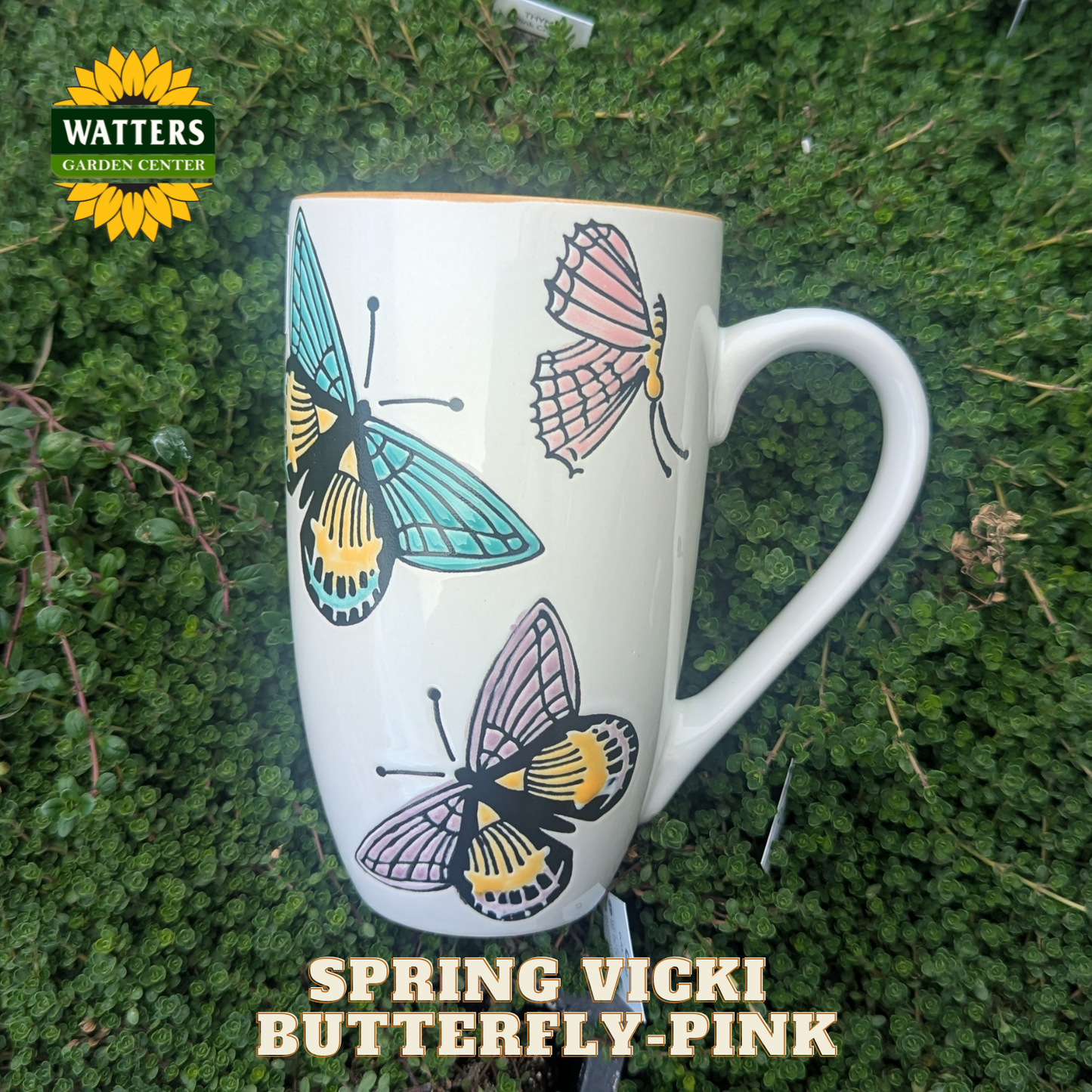 Mug with butterfly design on a green background, featuring Watters Garden Center branding.